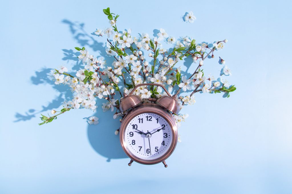 Vintage clock surrounded by white blossoms representing taking time for mental health and self-care