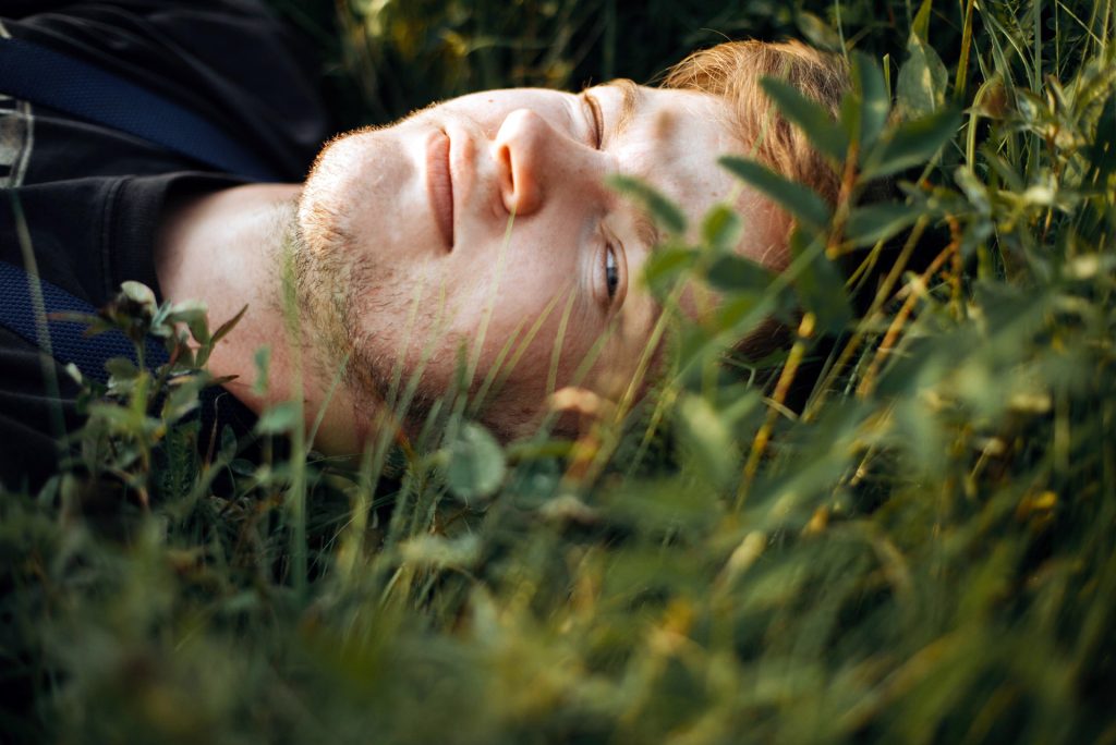 Person resting peacefully in grass representing rest and recovery through counselling