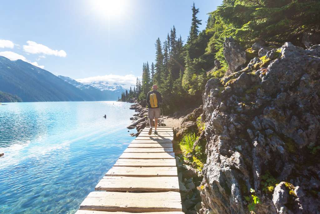 Person walking a boardwalk by a turquoise mountain lake representing the path of healing in BC