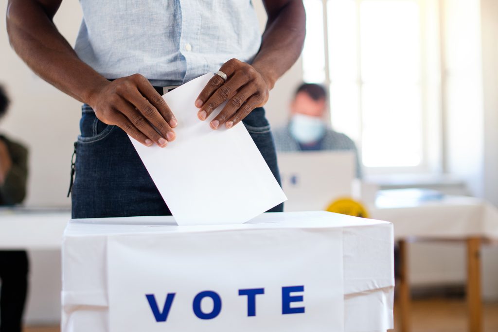Person casting a vote at ballot box representing political and social stress