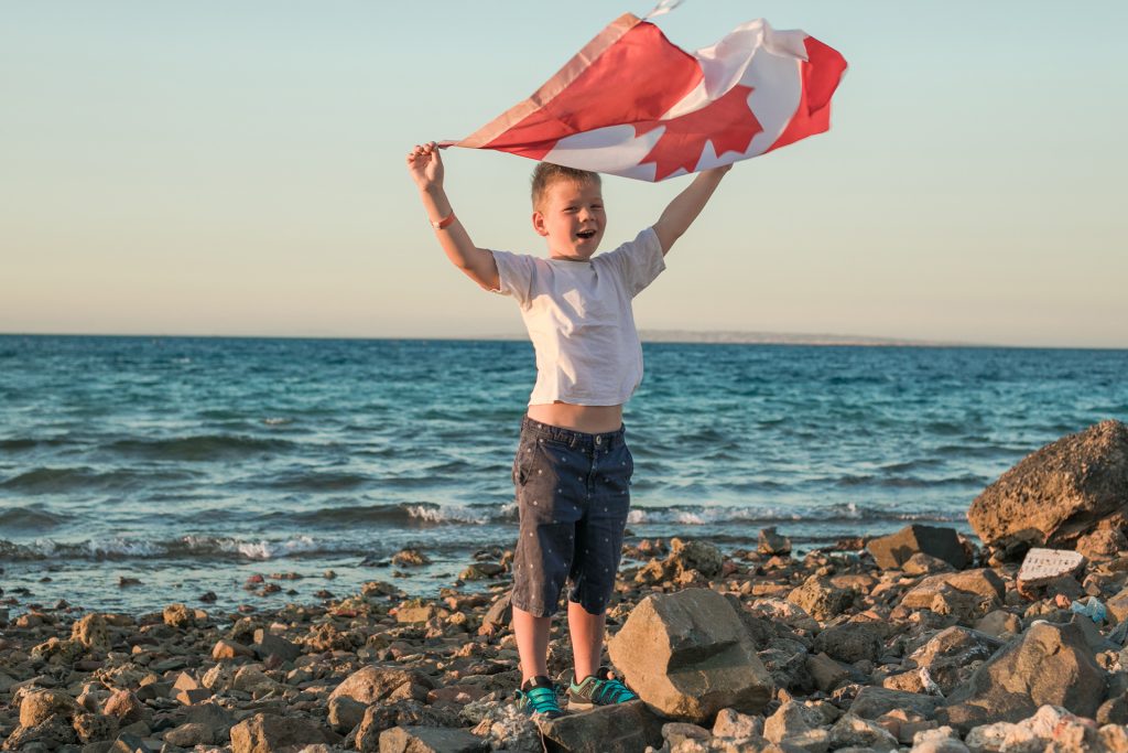 Child holding Canadian flag by the ocean honouring resilience of military families