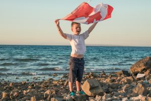 Child holding Canadian flag by the ocean honouring resilience of military families