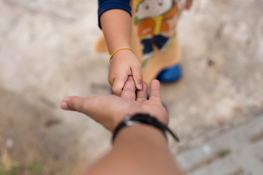 Adult reaching out to child's hand symbolizing anxious attachment and connection