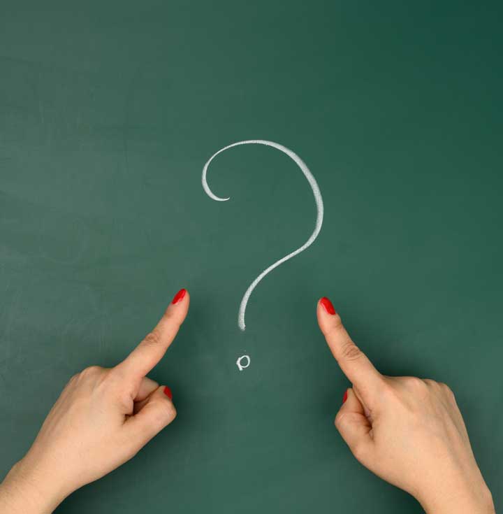 Hands pointing to a question mark on a chalkboard — representing common questions about counselling and therapy services in Abbotsford