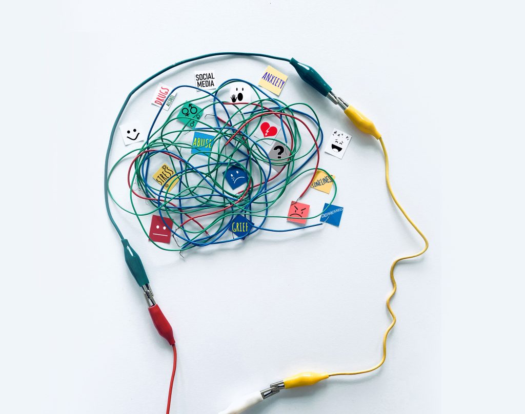 Illustration of a head filled with tangled wires labelled anxiety, stress, grief, and abuse — representing how trauma becomes stuck in the mind before EMDR therapy
